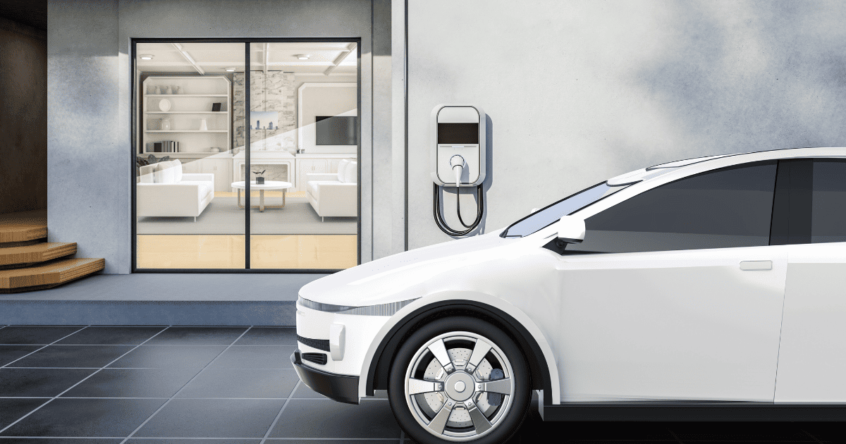 Image of a modern home with a white electric vehicle parked in the garage next to an EV charger .